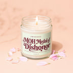 Lit candle in glass jar with "MOH Medal of Dishonor" label and petals.