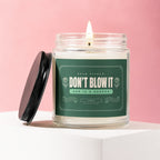 Glass candle with lit wick and black lid. Label reads "Dear Fiancé: Don't Blow It".