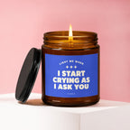 Amber glass candle with blue label reading "Light me when I start crying as I ask you."