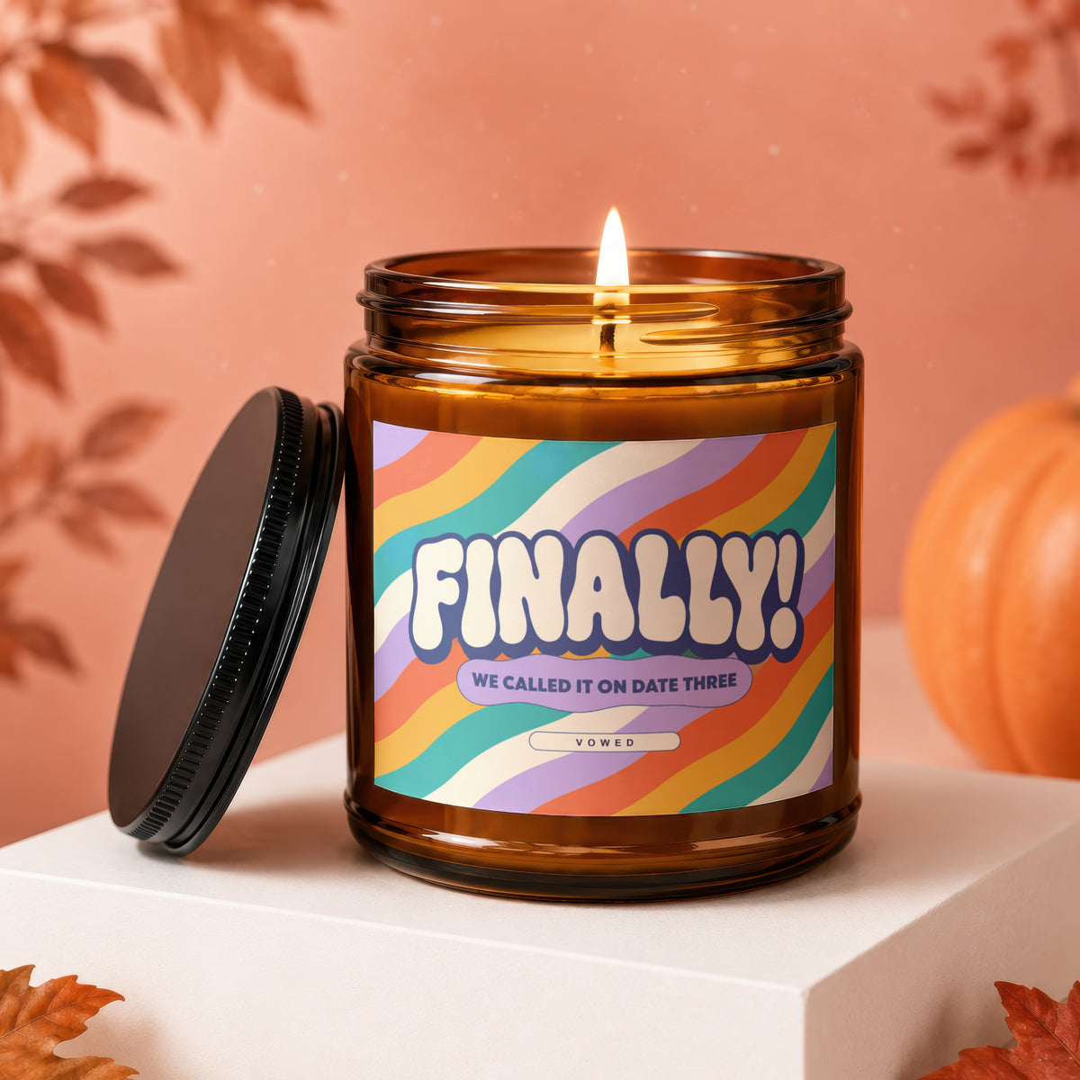 Amber jar candle with colorful label that reads "FINALLY! WE CALLED IT ON DATE THREE VOWED".