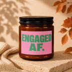 Amber jar candle with pink label reading "ENGAGED AF." and "vowed".