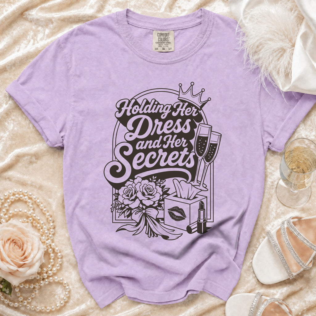Lavender t-shirt with "Holding Her Dress and Her Secrets" text and graphics.