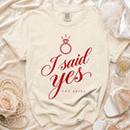 Cream t-shirt with red "I said yes THE BRIDE" text and diamond ring graphic.