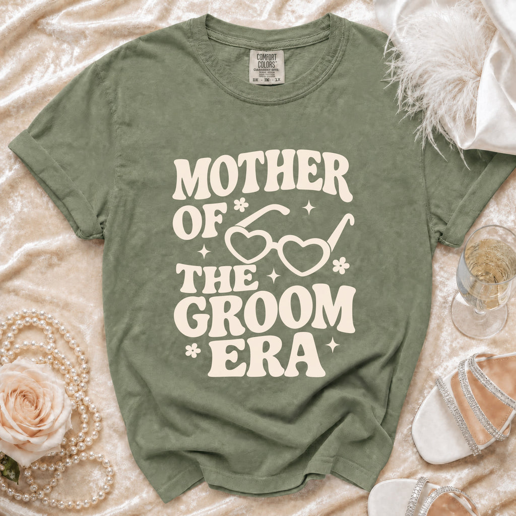 Green t-shirt with "Mother of the Groom Era" text and heart glasses graphic.