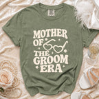 Green t-shirt with "Mother of the Groom Era" text and heart glasses graphic.