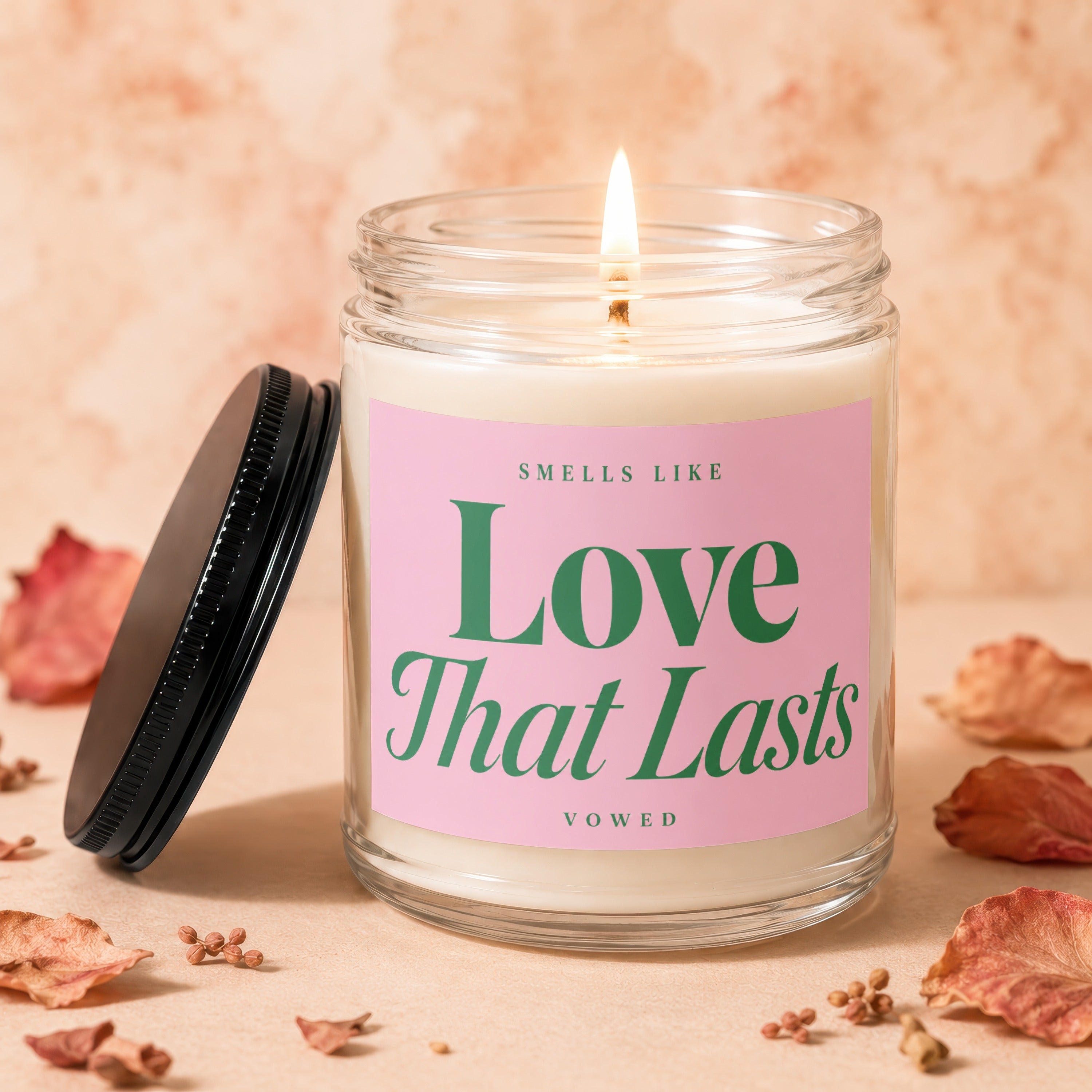 A lit candle in a glass jar with a pink label reading "Love That Lasts".