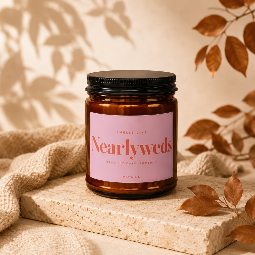 Amber candle with pink label reading "Nearlyweds", other text "Smells Like", "Save the Date, Someday", "Vowed".
