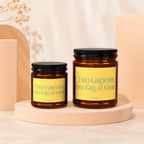 Two amber glass candles with yellow labels reading "Two Grooms, One Great Story".