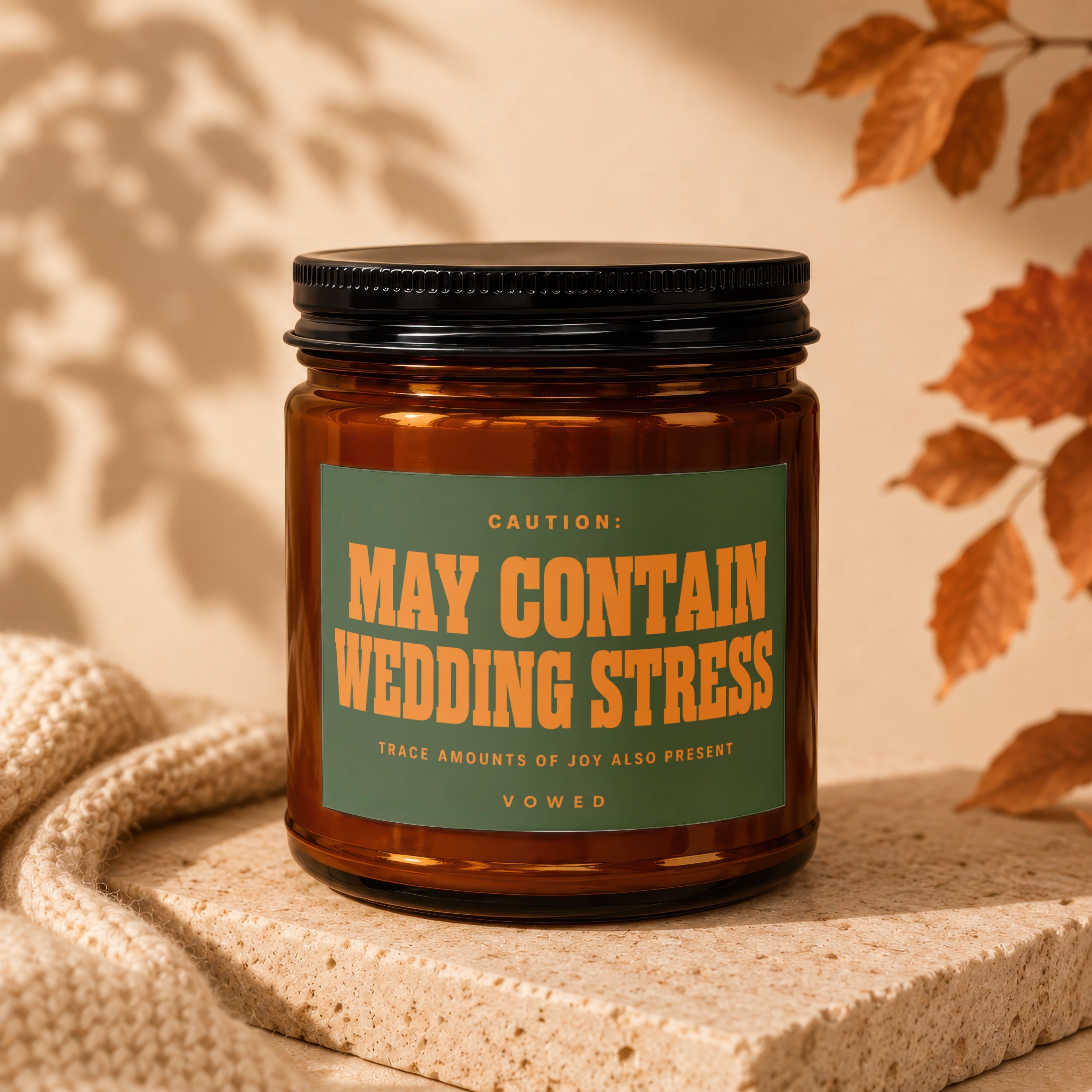 Amber candle with green label reading "CAUTION: MAY CONTAIN WEDDING STRESS" and "VOWED".