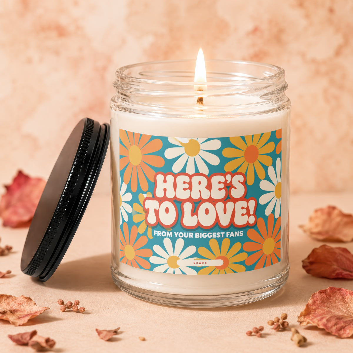 Candle with "HERE'S TO LOVE! FROM YOUR BIGGEST FANS" text and floral design.