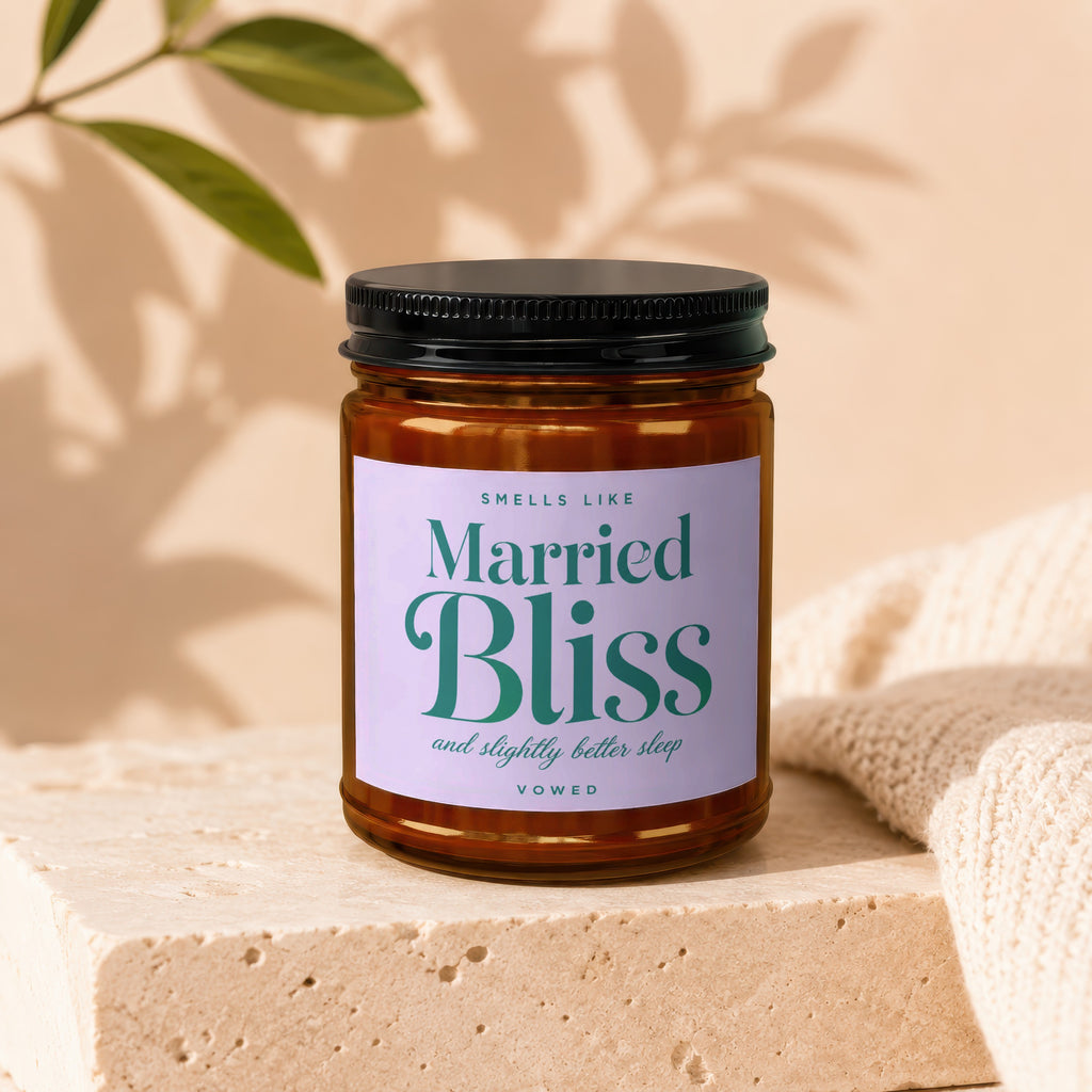 Amber glass candle labeled "Smells Like Married Bliss and slightly better sleep VOWED".