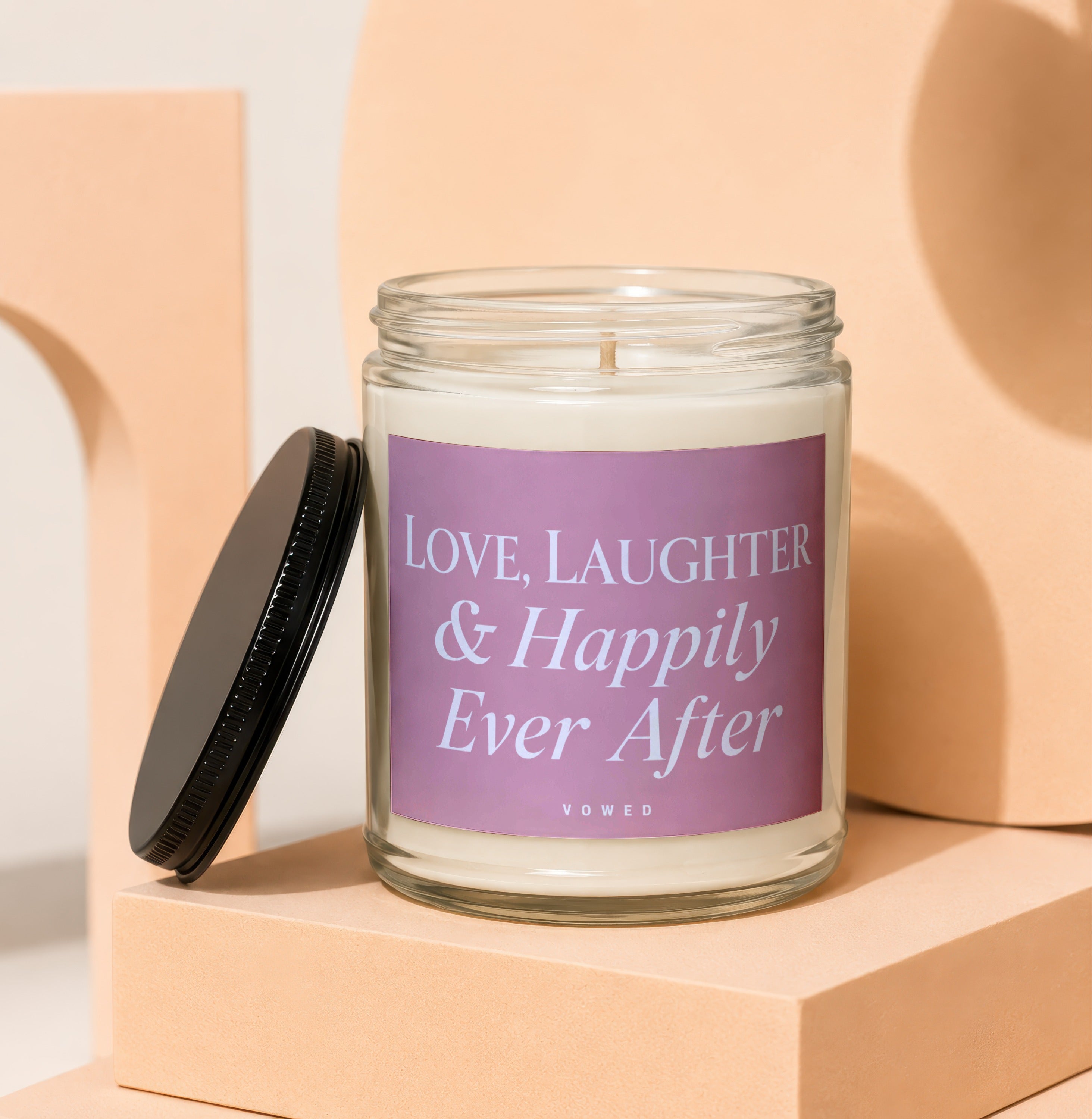 Glass candle with purple label: "Love, Laughter & Happily Ever After VOWED".