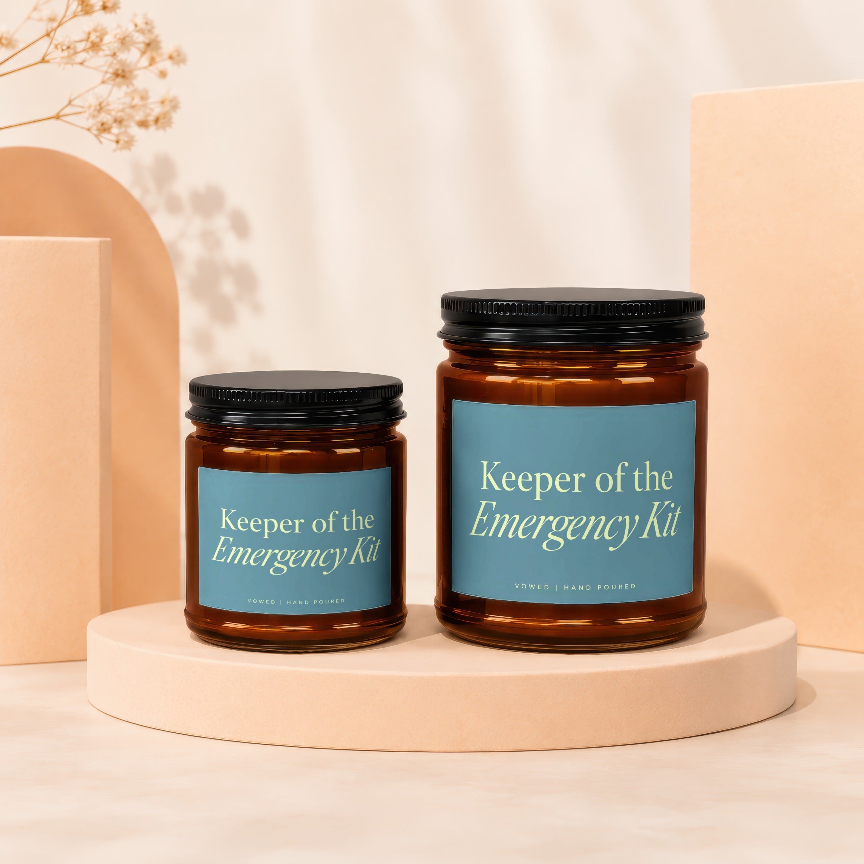 Two amber glass candles with blue labels reading "Keeper of the Emergency Kit".