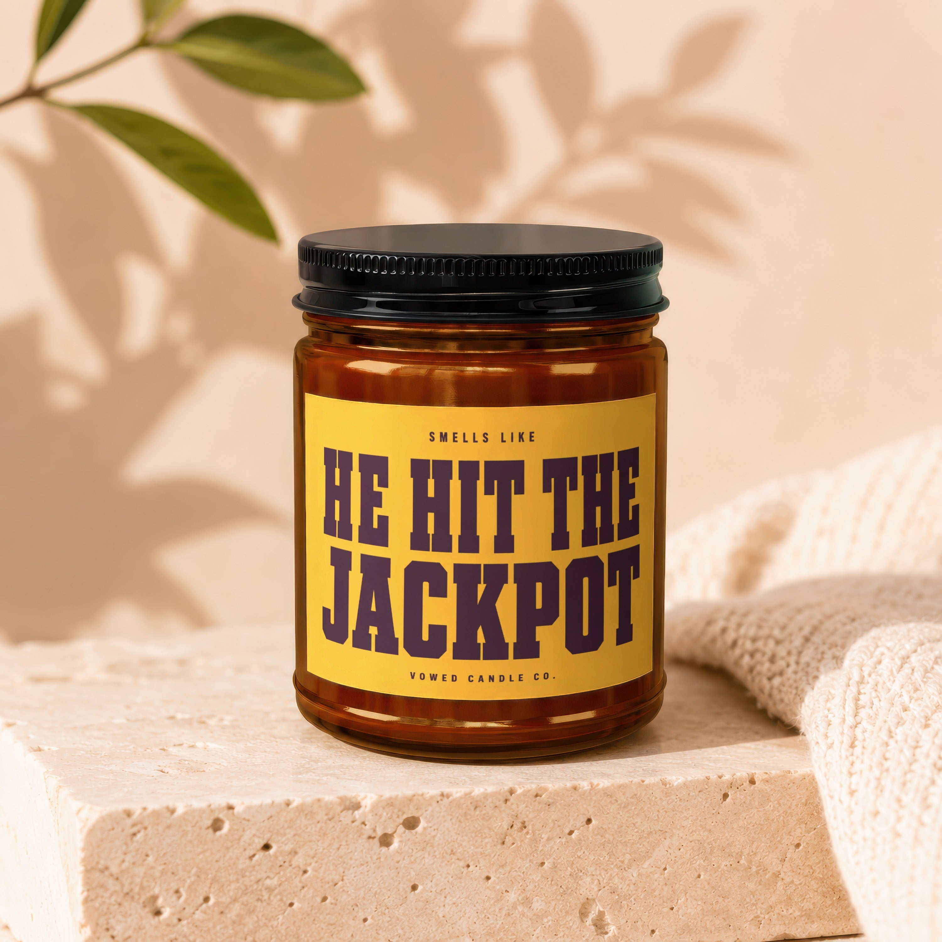 Amber jar candle with "Smells like HE HIT THE JACKPOT" on yellow label.