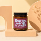 Amber jar candle with purple label reading "Two grooms, no bride, no problem VOWED."