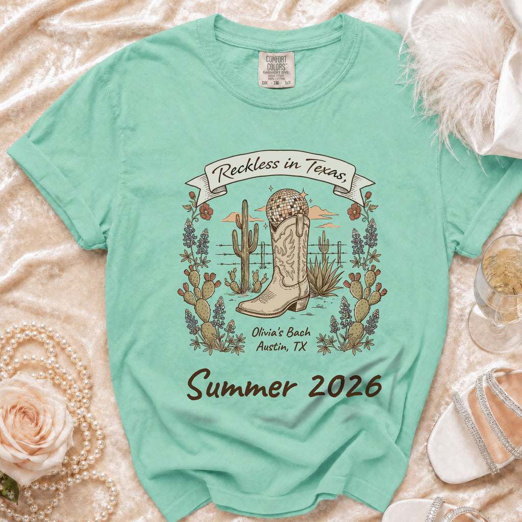 Green t-shirt with "Reckless in Texas" and cactus, boot, disco ball graphics.