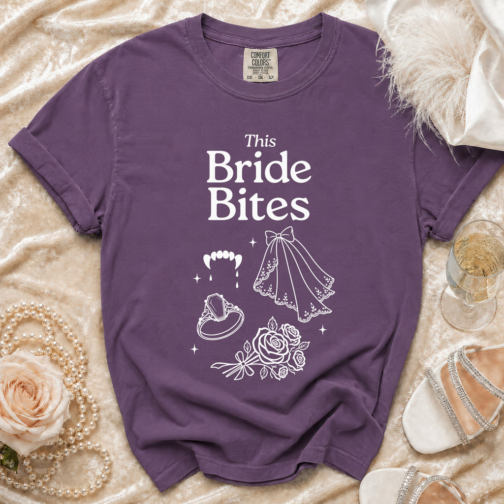 Purple t-shirt with "This Bride Bites" text, fangs, ring, veil, and roses.