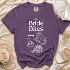 Purple t-shirt with "This Bride Bites" text, fangs, ring, veil, and roses.