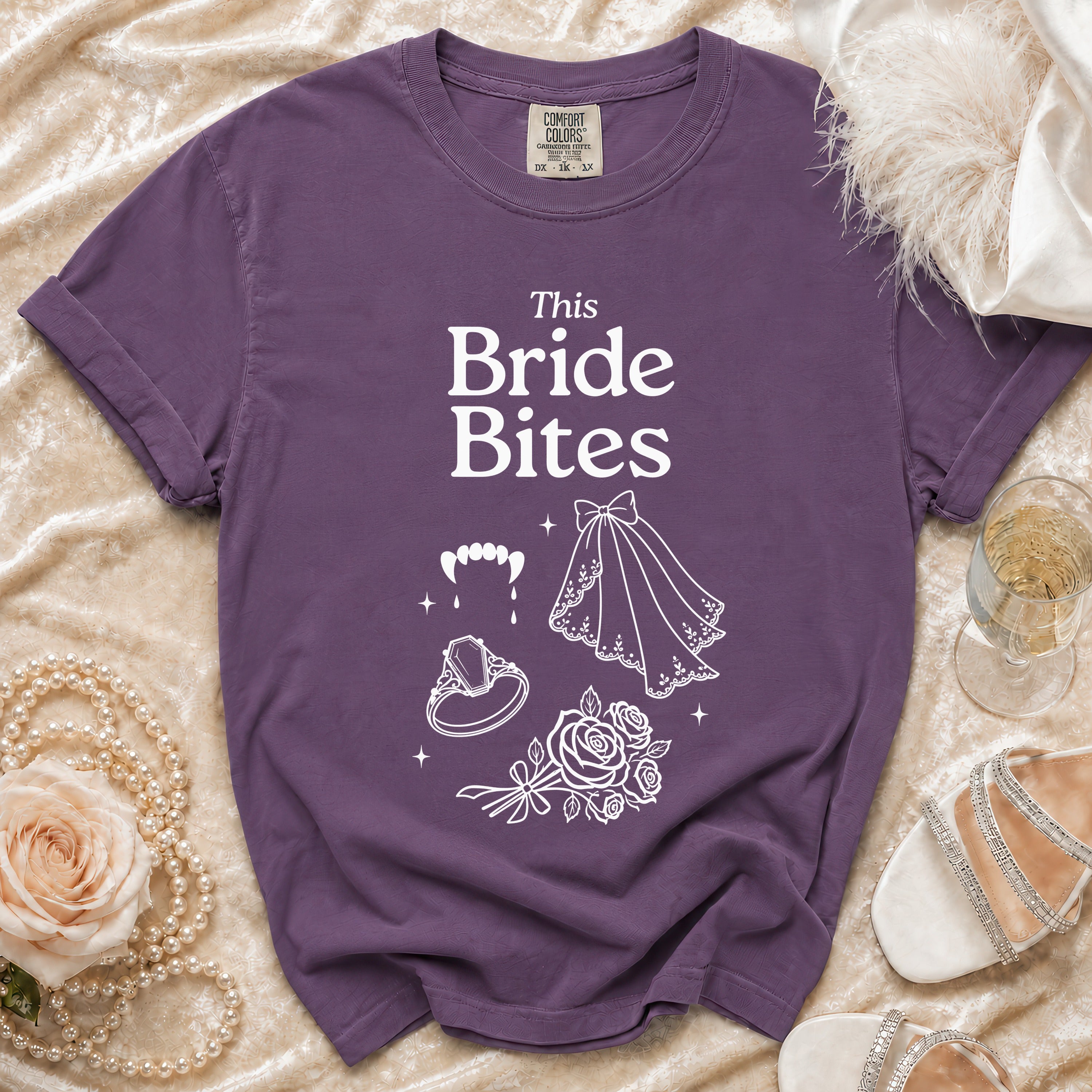 Purple t-shirt with "This Bride Bites" text, fangs, ring, veil, and roses.