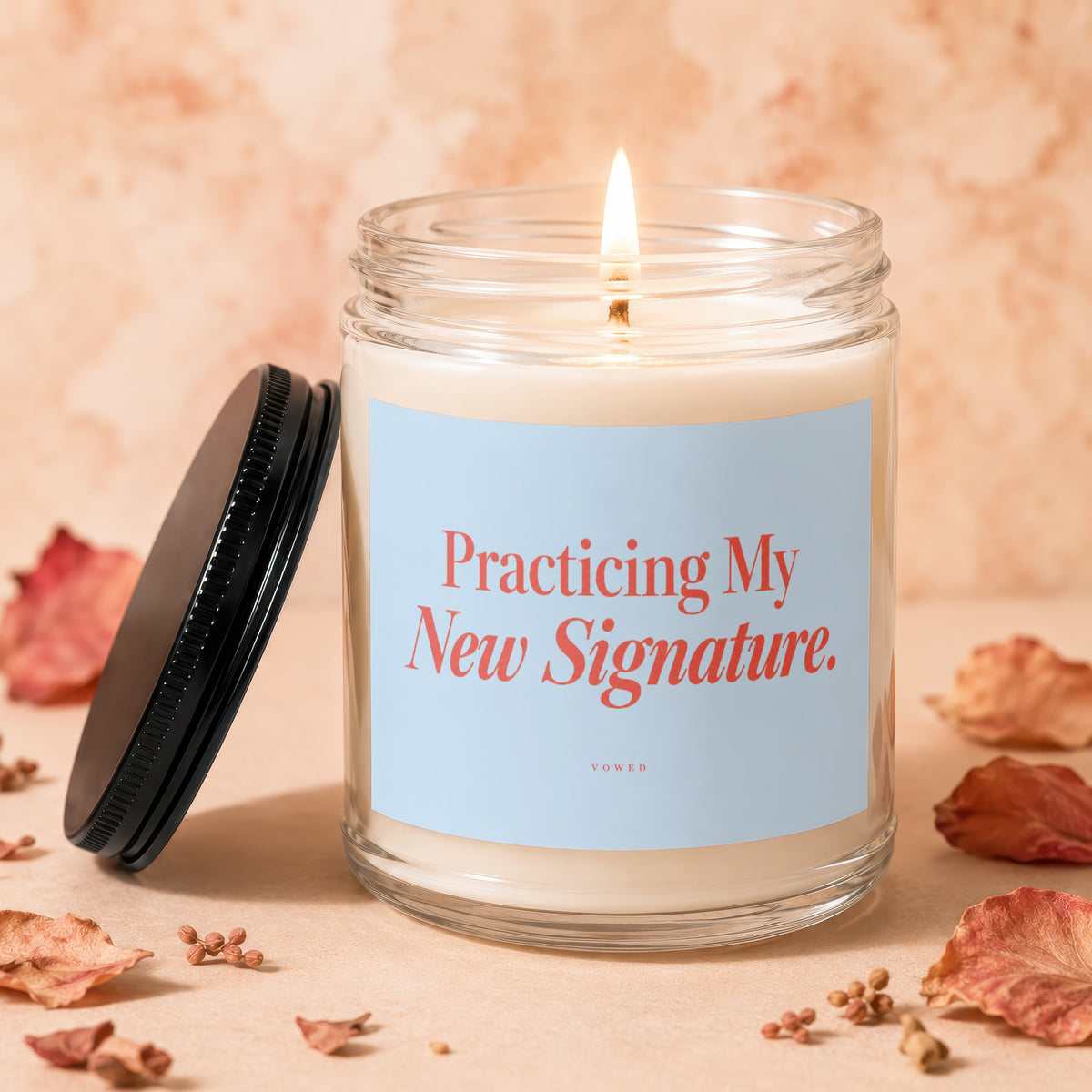 Candle with lit wick and "Practicing My New Signature." text, lid beside it.