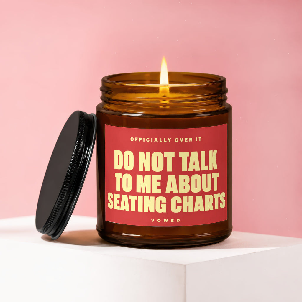Burning amber glass candle with red label: "DO NOT TALK TO ME ABOUT SEATING CHARTS".