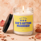 Glass candle with a lit wick and yellow label reading "She's Getting Married!"