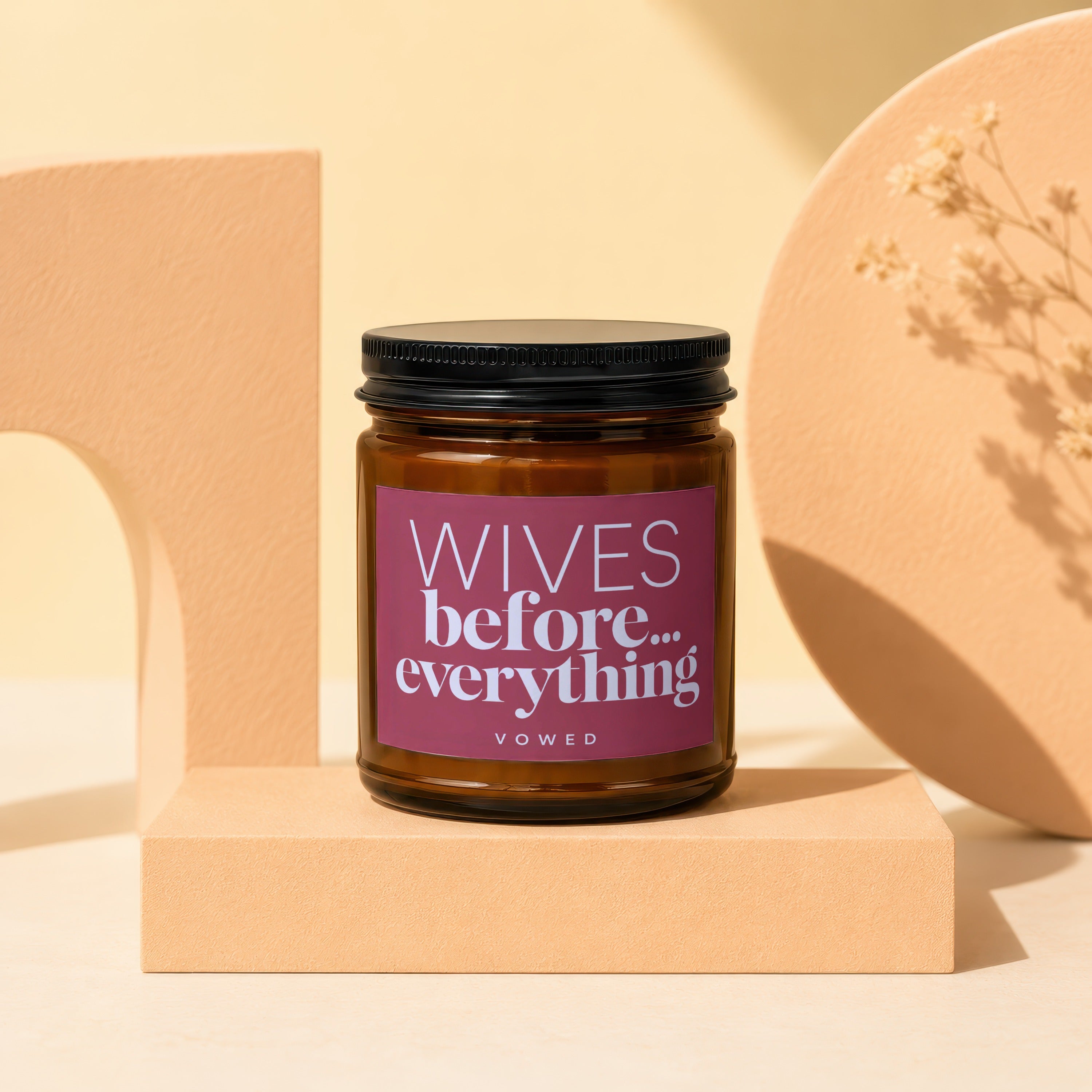 Brown glass candle with "WIVES before... everything" label on a peach pedestal.