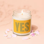 A lit candle in a glass jar with "Smells Like YES" on the label.