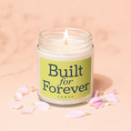 Glass jar candle with lit wick, green label reads "Built for Forever VOWED."
