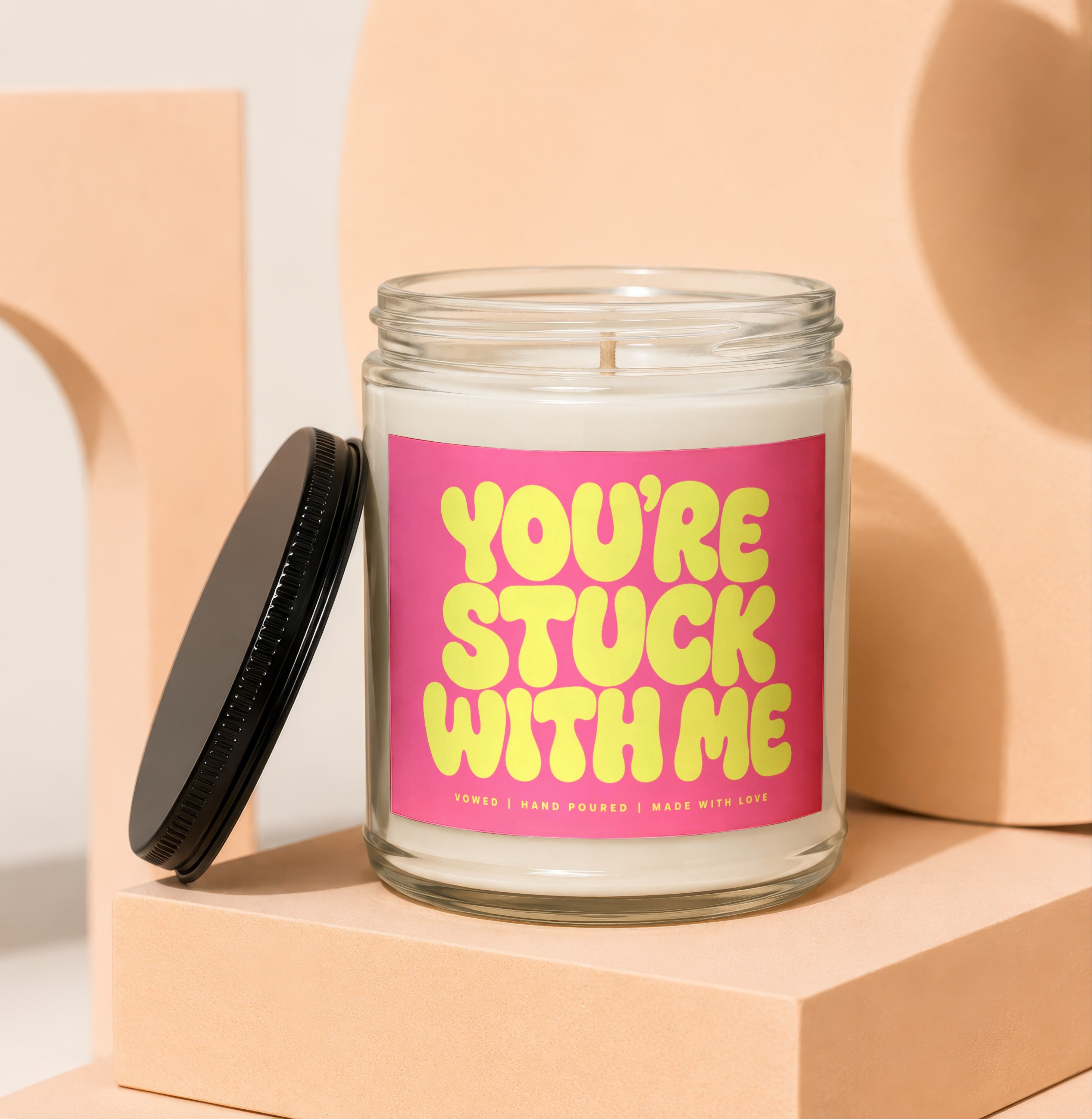 Glass candle with a pink label featuring yellow text "YOU'RE STUCK WITH ME".