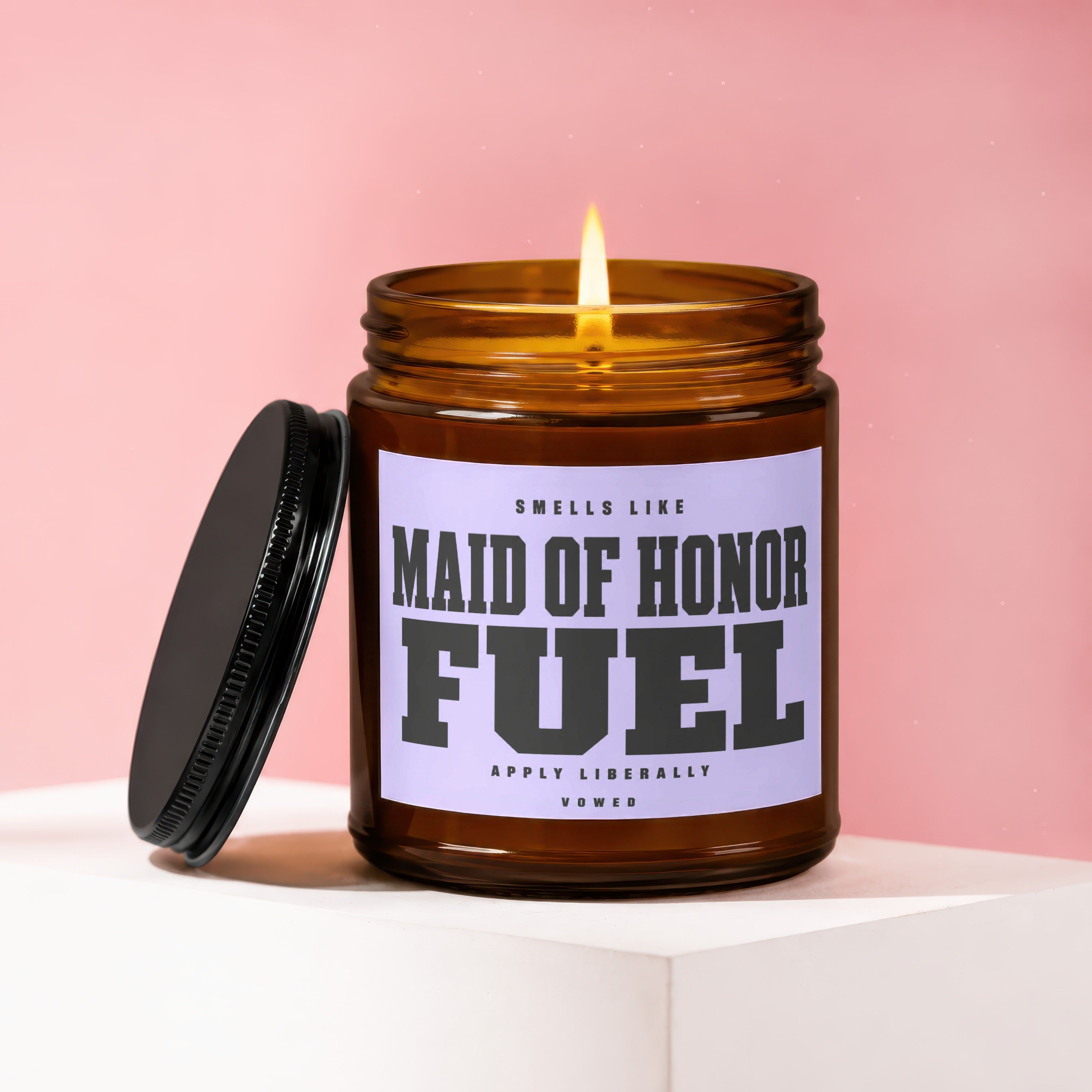 Amber candle with lit wick, lid off, labeled "Maid of Honor Fuel".
