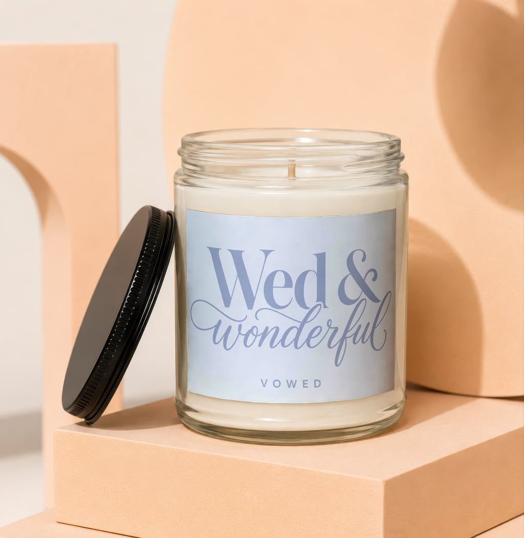 Glass jar candle with a black lid and a label that reads "Wed & wonderful VOWED".