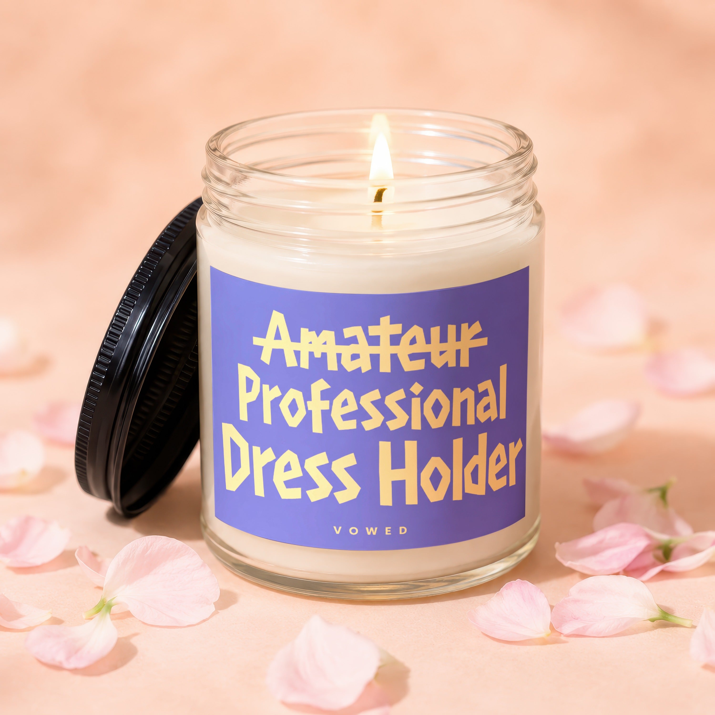 Lit candle in a glass jar with purple label that reads "Amateur Professional Dress Holder VOWED".