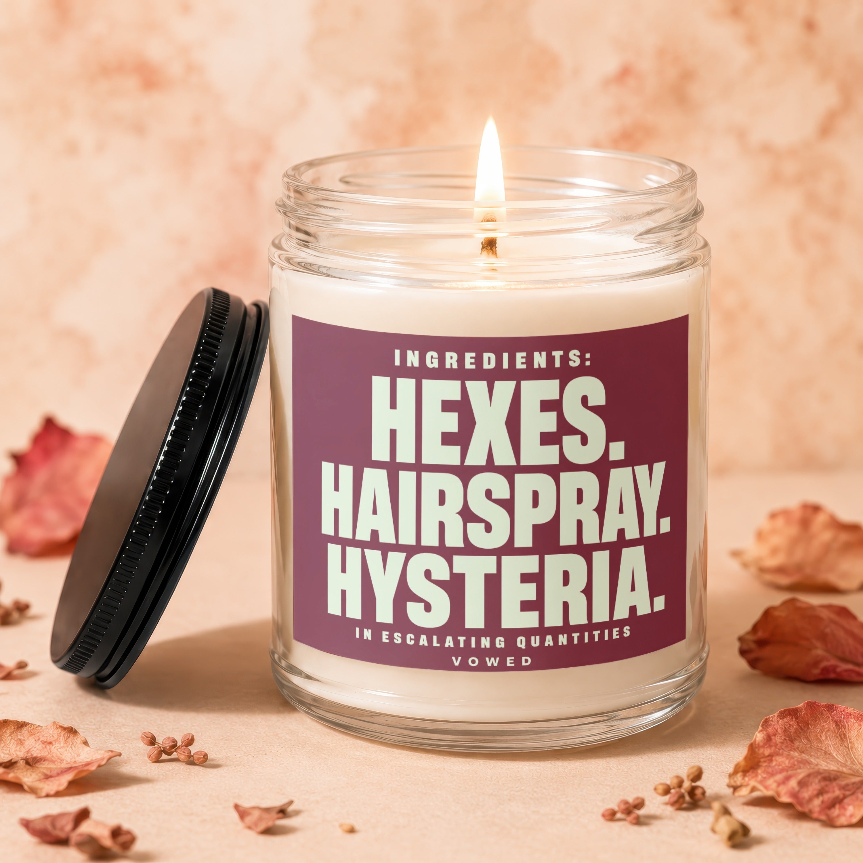 Lit candle with label "Ingredients: Hexes. Hairspray. Hysteria. In escalating quantities."