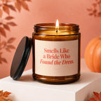 Amber candle with lit wick, reads "Smells Like a Bride Who Found the Dress."