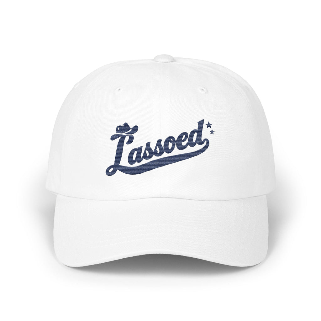 A white baseball cap featuring navy blue embroidered text that reads Lassoed with a cowboy hat and stars.