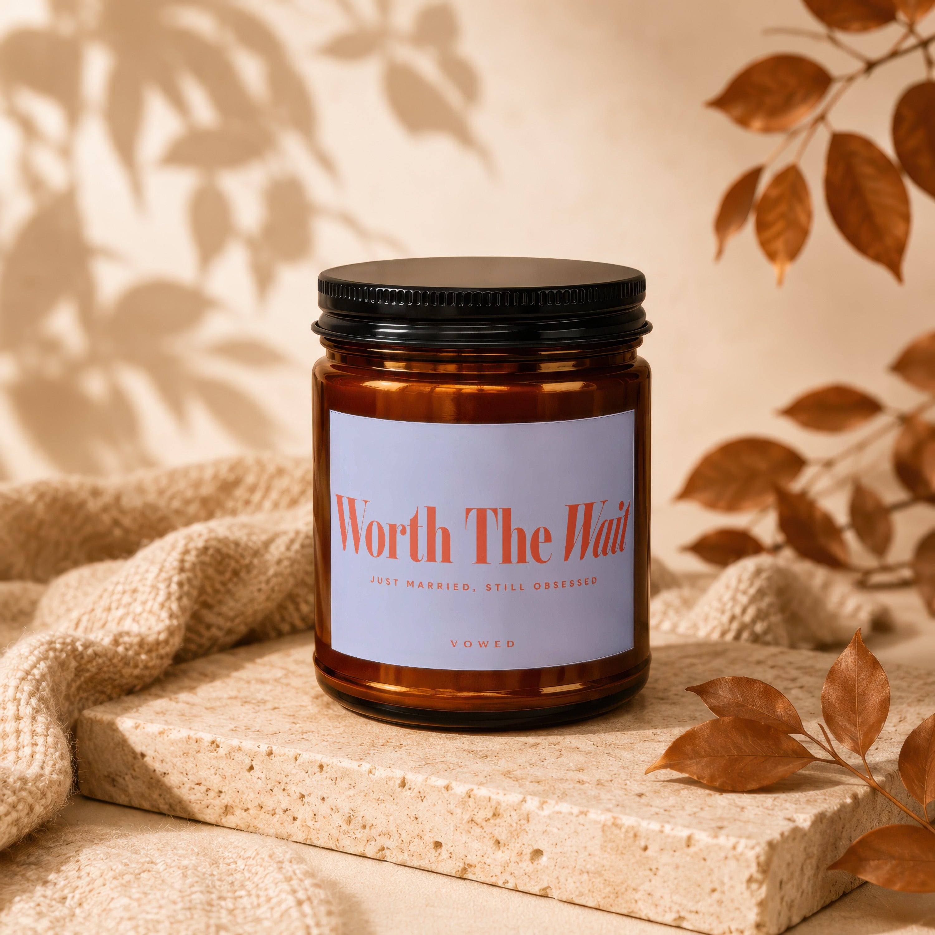 Amber jar candle with black lid and white label reading "Worth The Wait".