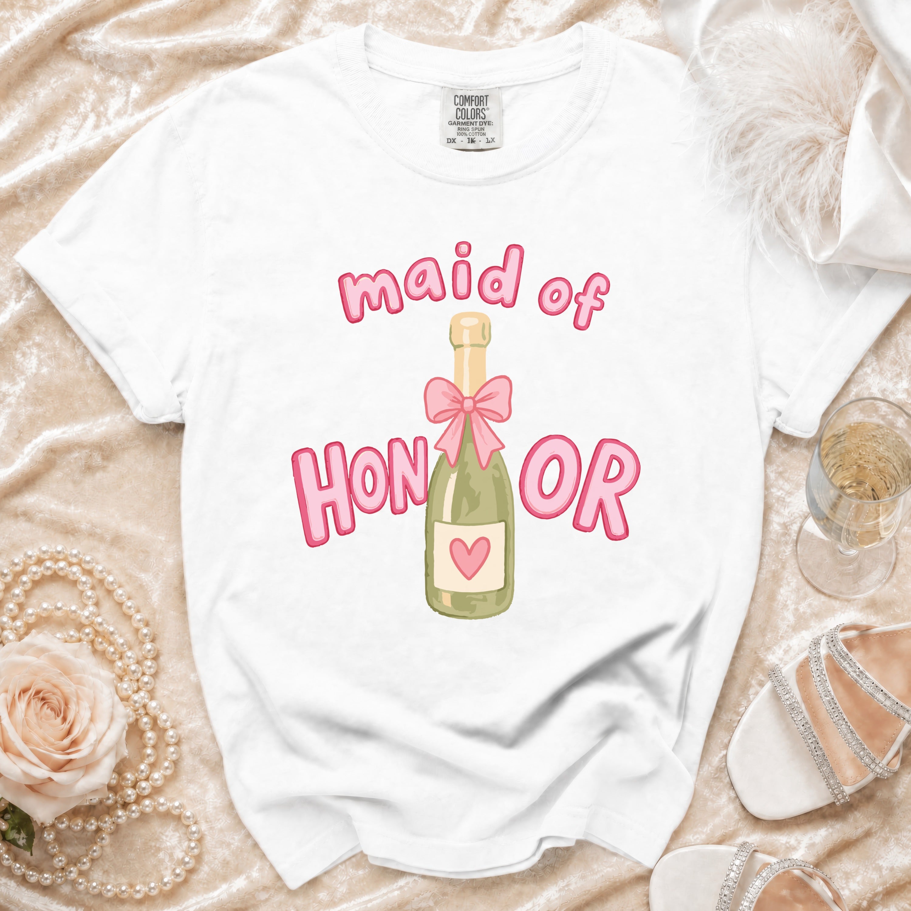 White t-shirt with "maid of HONOR" text and champagne bottle graphic.