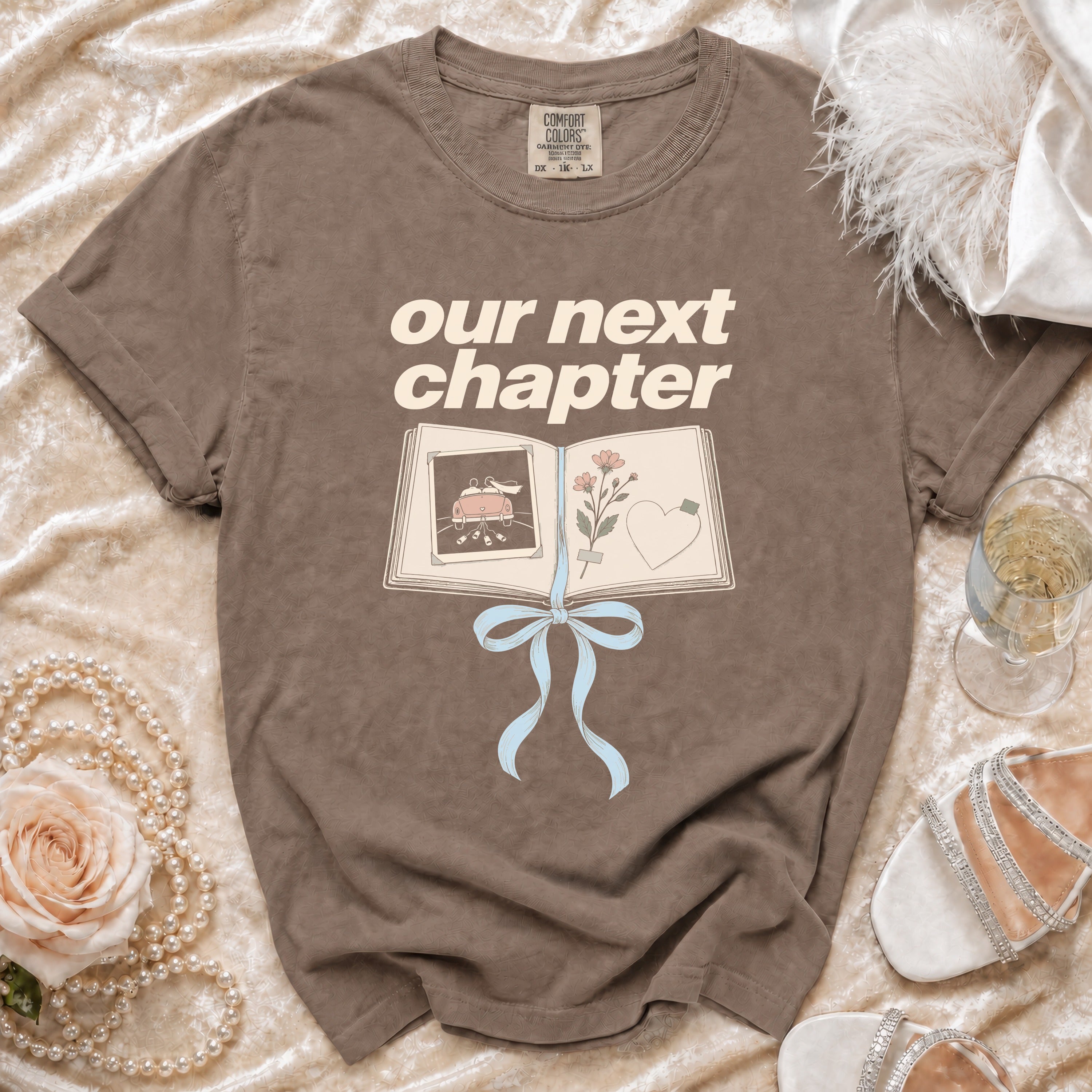 Brown t-shirt with "our next chapter" text and open book graphic.