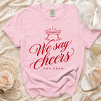 Pink Comfort Colors t-shirt with red "We say Cheers THE CREW" graphic.