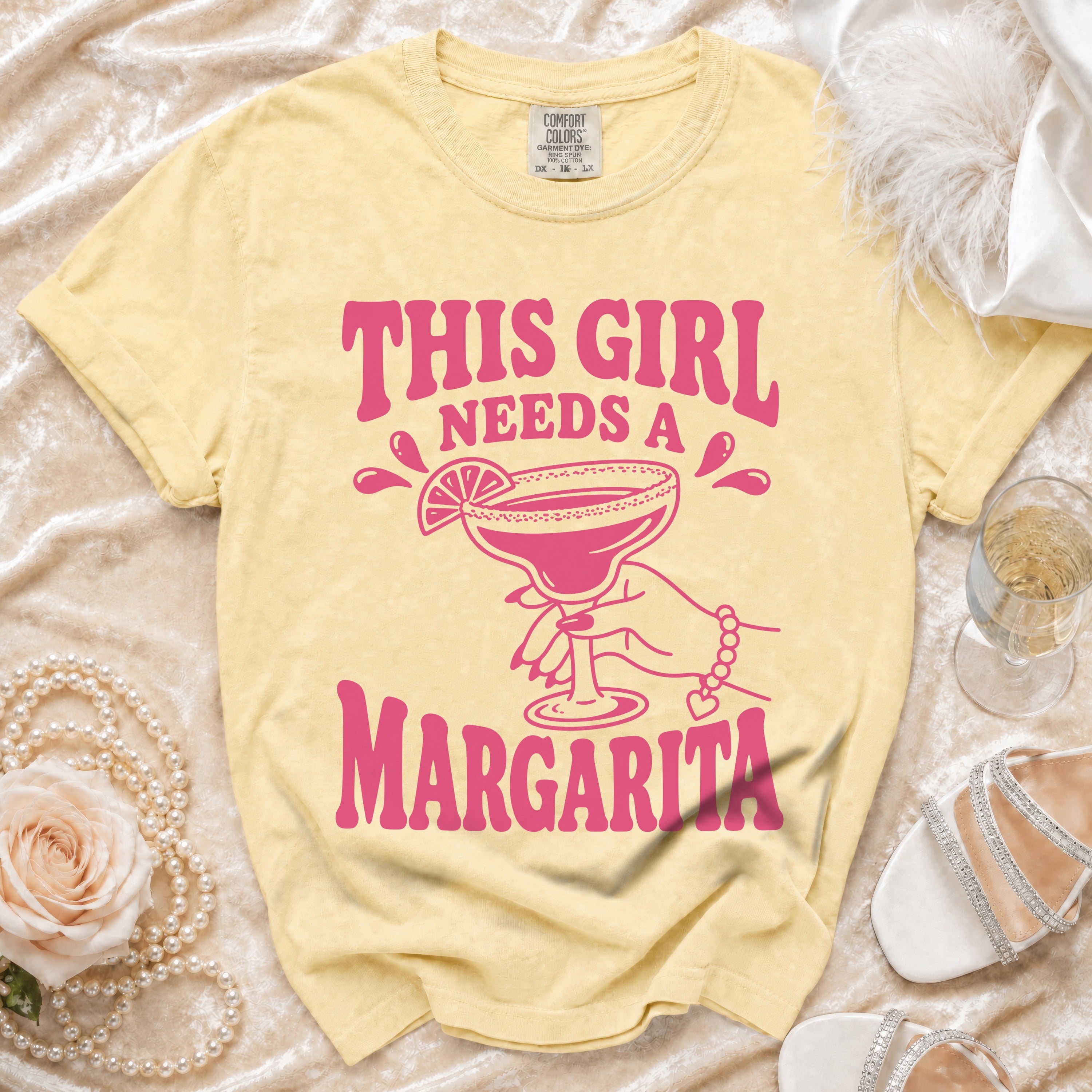 Yellow t-shirt with pink text "This Girl Needs A Margarita" and graphic.