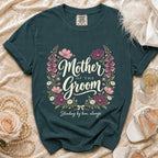 Teal t-shirt with "Mother of the Groom" floral design and "Standing by him, always".