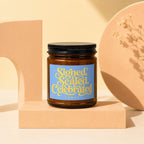 Brown glass candle with blue label featuring yellow text "Signed, Sealed, Celebrated Vowed".