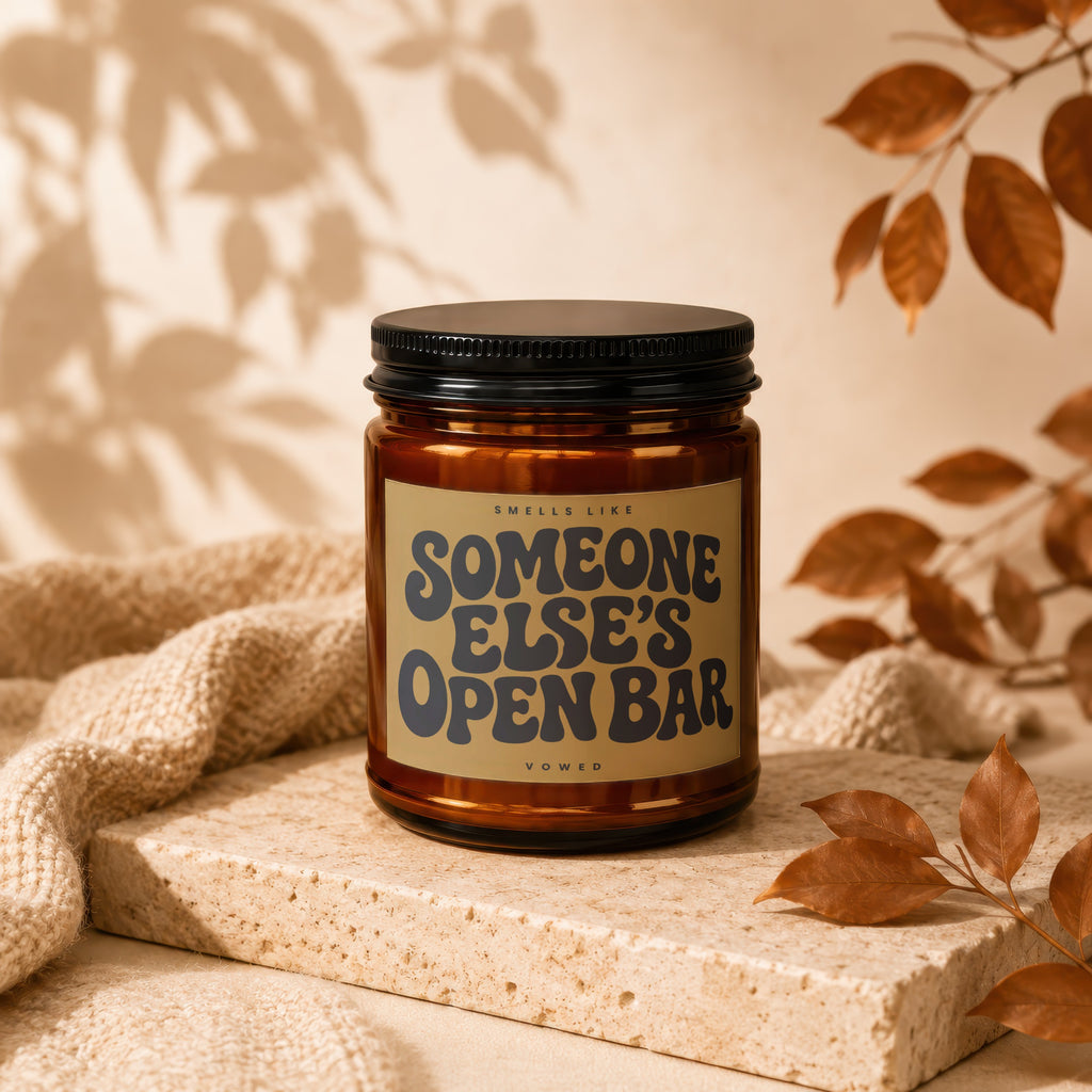 Amber candle with black lid featuring "Smells Like Someone Else's Open Bar" text.