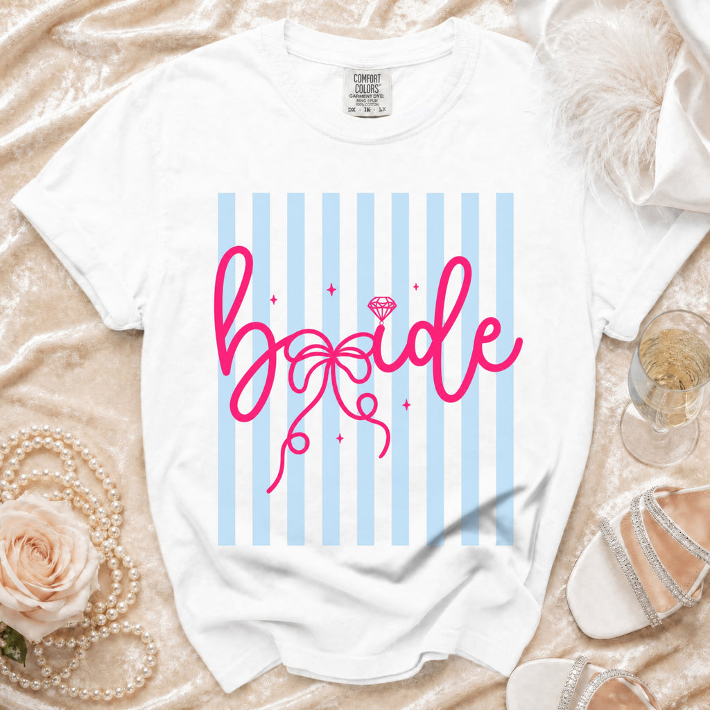 White t-shirt with pink "bride" graphic and diamond on blue striped background.