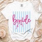 White t-shirt with pink "bride" graphic and diamond on blue striped background.