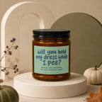 Candle with text "will you hold my dress while I pee?" and "hand poured".