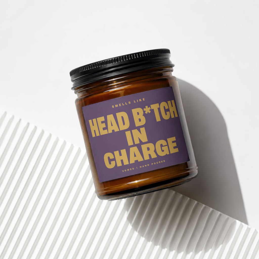 Candle with a purple label reading "Smells like Head B*tch In Charge".