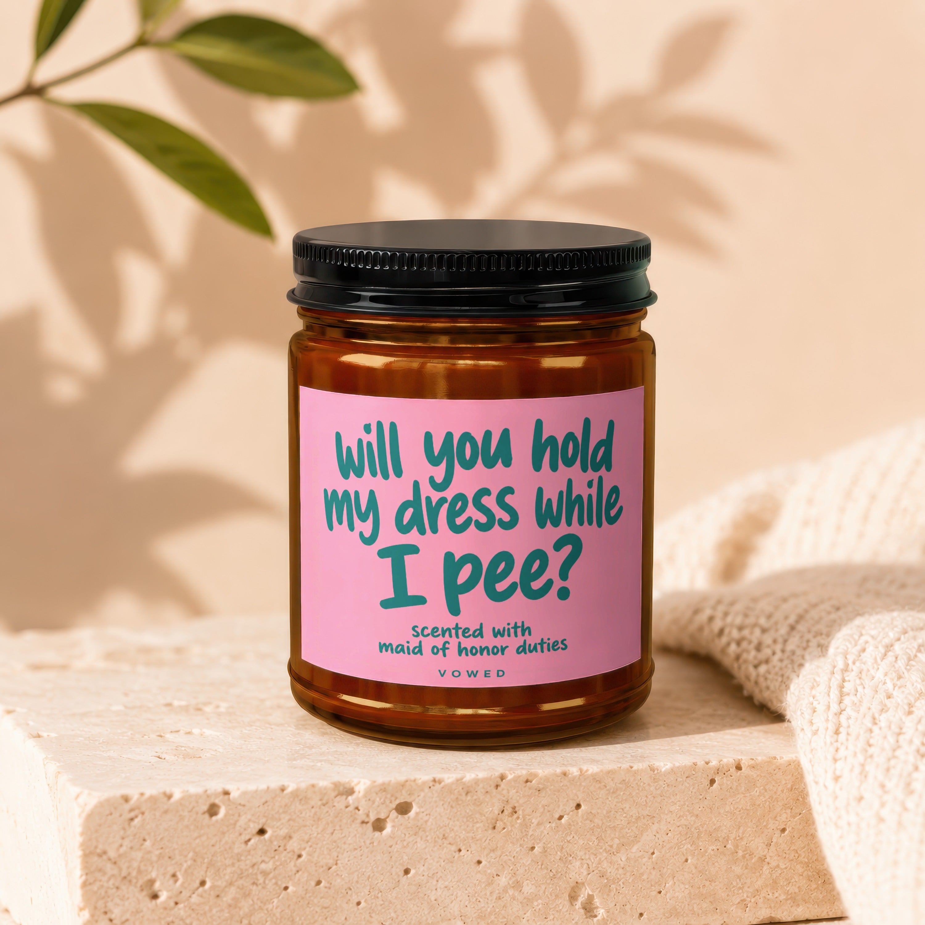 Candle with pink label reading "will you hold my dress while I pee?"