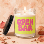 Candle with a lit wick and a label that reads "OPEN BAR LOADING... VOWED".